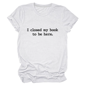 Gros plan du texte noir imprimé I closed my book to be here sur le t-shirt blanc en coton