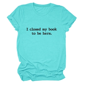 Détail à plat du t-shirt turquoise avec l'imprimé texte 'I closed my book to be here' en noir