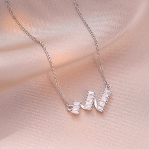 Elegant wavy zircon pendant necklace with rectangular stones on champagne silk background