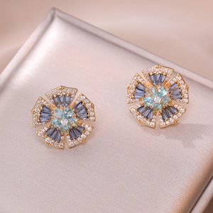 Elegant gold flower stud earrings with blue trapezoid gems and white crystal accents