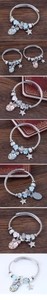 Detailaufnahme von silbernem Kabelarmband mit bunten Herzanhängern auf holzigem Hintergrund
