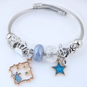 Nahaufnahme von Silberarmband mit blauen Stern- und Hasenanhängern auf weißem Grund