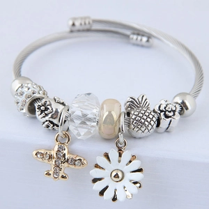 Detailed macro view of silver wire rope bracelet with airplane and daisy charms