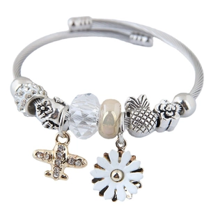 Silver charm bracelet featuring airplane, daisy, and pineapple pendants on woven band