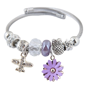 Silver woven bracelet with purple daisy, airplane charm, and crystal beads on white