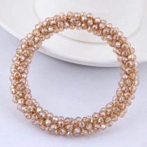 Détail d'un bracelet en perles de cristal champagne facetté sur une table blanche