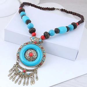 Detail of bohemian long necklace featuring bronze pendant with tassels and turquoise beads