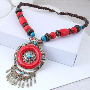 Detail of bohemian ethnic necklace with red resin beads and bronze tassel pendant