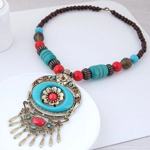 Ethnic necklace detail featuring bronze pendant, red beads and metal tassels