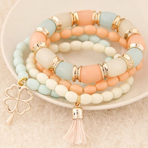Elegant four-piece layered beaded bracelet set with four-leaf clover charm and tassel fringe