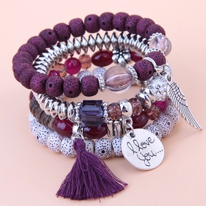 Detail of bohemian layered beaded bracelet with purple tassel and silver wing charm