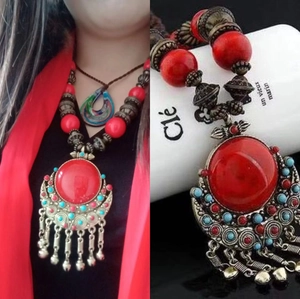 Ethnic long pendant necklace with red gemstone and silver bell tassels displayed on model