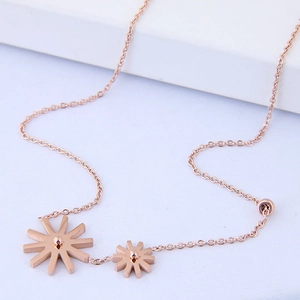 Rose gold stainless steel double daisy pendant necklace on minimalist white platform