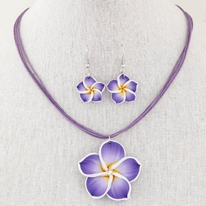 Elegantes Set aus lila Plumeria-Halskette und Ohrringen auf einer grauen Büste