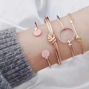 Elegant 4-piece gold bangle set with knot, heart pendant, and rhinestone accents