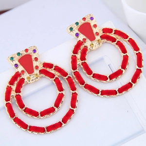 Macro detail of gold-tone circle earrings featuring red velvet weave and colorful rhinestones