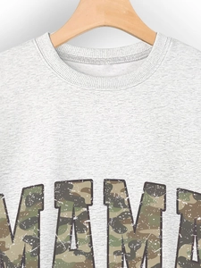 Close-up of MAMA camo print and fabric texture on light grey long sleeve sweatshirt