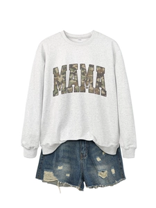Flat lay of gray sweatshirt featuring camouflage MAMA print and distressed denim shorts