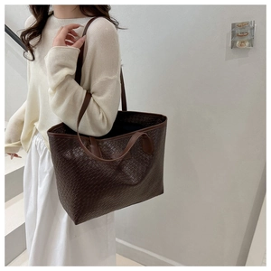 Detail of dark brown woven tote bag with large capacity and slim leather shoulder straps