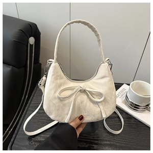 Detail of a creamy white bow handbag with wrinkled texture and silver hardware details