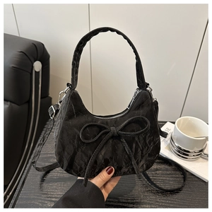 Detail of black crescent hobo bag with oversized bow and textured ruched fabric design