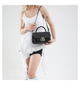 Detail of black glitter crossbody bag with gold metal clasp and wide top handle