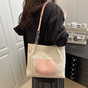Borsa tote in paglia con tasca in pelle rosa e tracolla a catena indossata da modella