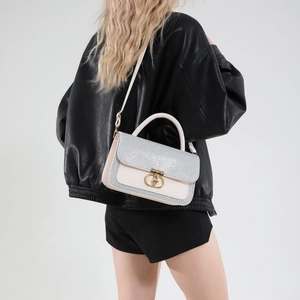 Elegant ivory crossbody bag with sparkling flap and gold D-clasp on model