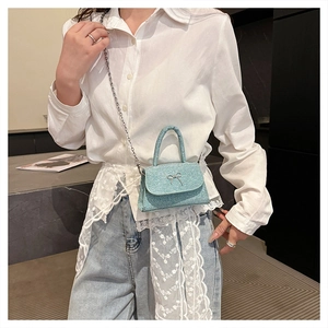 Detail of light blue glitter crossbody bag with silver bow accent and chain strap