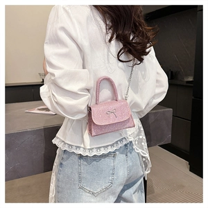 Close-up of pink sequined crossbody bag with silver bow accent and metal chain strap