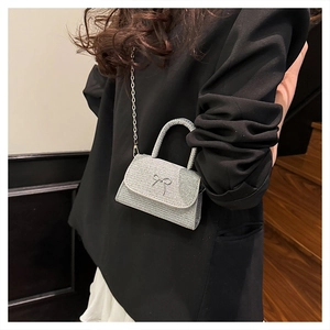 Silver bow shoulder bag with glitter finish and elegant chain strap on model