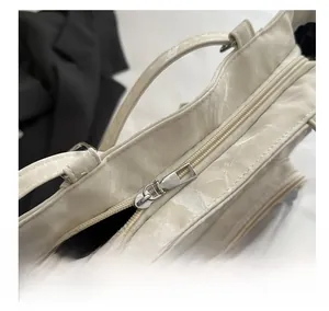 Detail of smooth silver zipper and stitching on cream tote bag with marble texture
