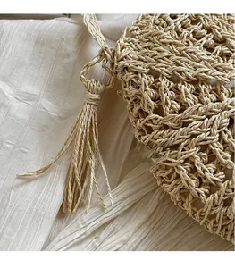 Detail of hand-woven straw bag texture featuring long tassels and soft fabric lining