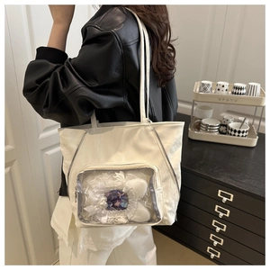 Detail of white ita tote bag showing large clear window with anime badges and accessories