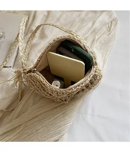 Detail view of woven straw shoulder bag interior with phone and cosmetics inside