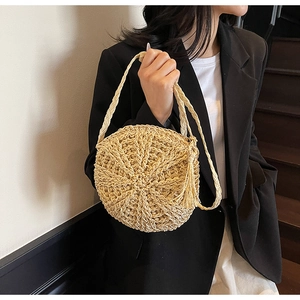 Detail of round straw bag showing intricate weave pattern and boho tassel accessory