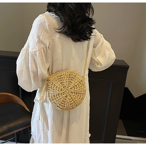 Detail of round straw shoulder bag with woven radial pattern and fringe tassel