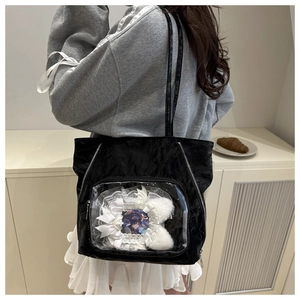Detail of a black ruffled tote bag featuring a clear ita-bag window with lace and bows