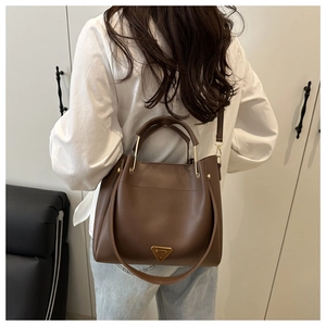 Detail view of the brown leather square tote bag shown on model for a casual styling look