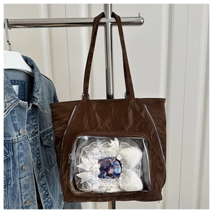 Detail of dark brown ita bag tote featuring a clear window for anime pins and lace decor