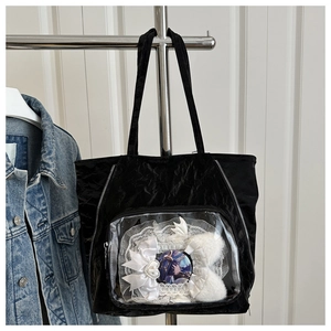 Detail of black pleated tote bag featuring a clear PVC window for character badges