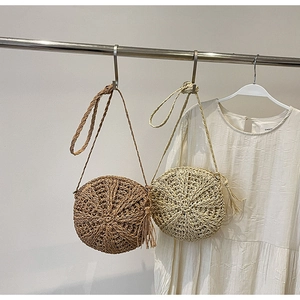 Detailed close-up of round straw shoulder bags with tassels and woven geometric textures