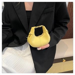 Detailed macro of vibrant yellow half-moon leather bag with golden metallic hardware