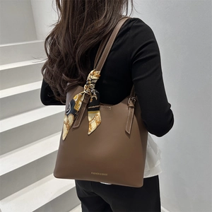 Large brown leather tote bag with elegant silk scarf detail and golden logo accent