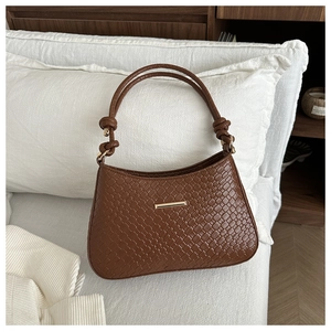 Détail du sac à main tissé marron foncé avec boucle dorée et poignée nouée élégante