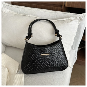 Détail du sac à bandoulière tressé noir avec boucles dorées et bandoulière nouée