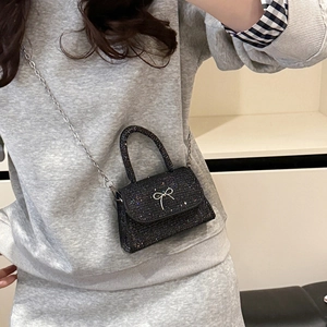 Sparkly black bow crossbody bag with silver chain strap shown on model for sizing