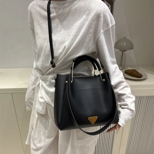 Sac bandoulière chic en cuir noir avec poignée et logo triangulaire métallique iconique