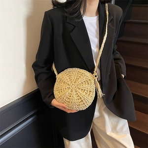 Handwoven round straw crossbody bag with tassels and shoulder strap on model