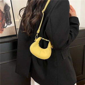 Mini yellow PU crescent bag with shoulder strap worn over a black blazer back view